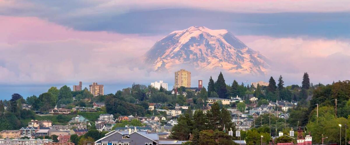 A photo of Tacoma, Washington, shows the city between water and the mountains.
