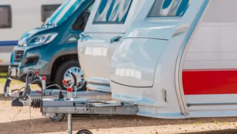 An organized line of RVs are parked in a storage lot.