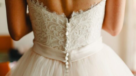 A woman is wearing a wedding dress with buttons up the back.