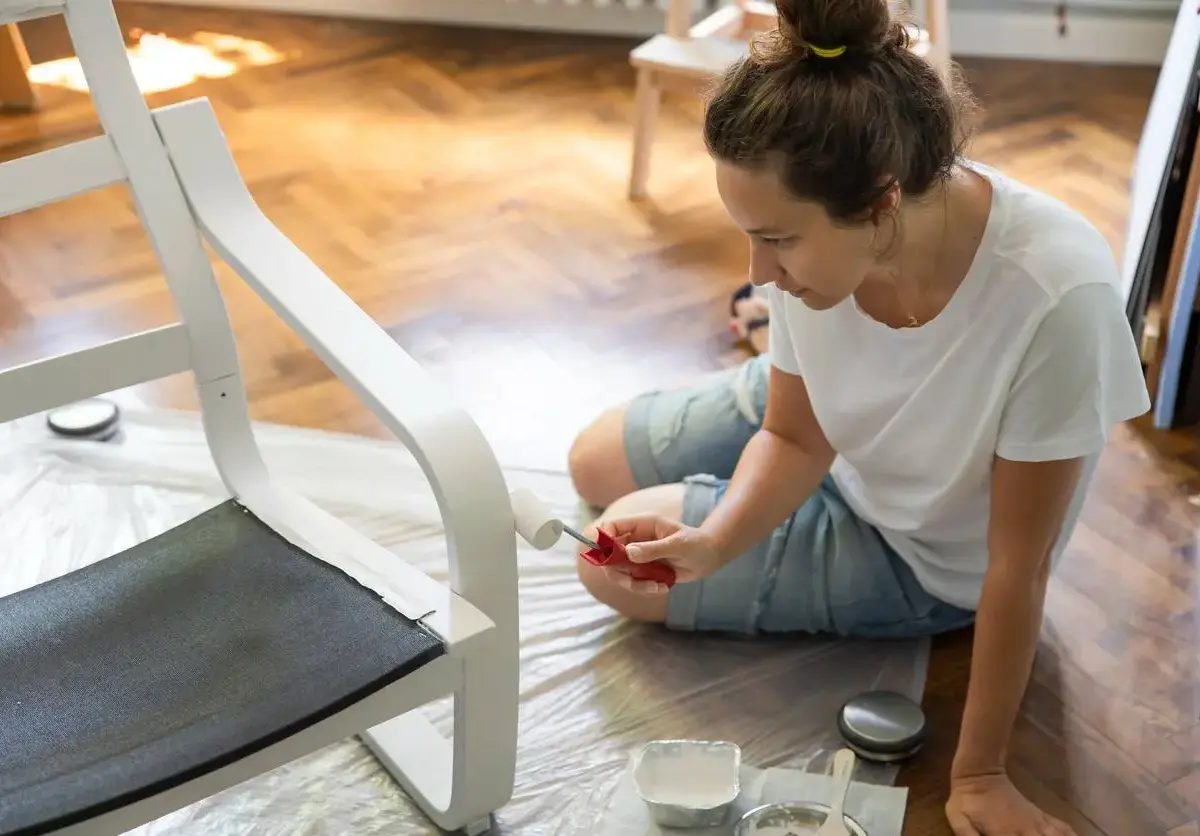 Woman painting a chair in her livingroom.