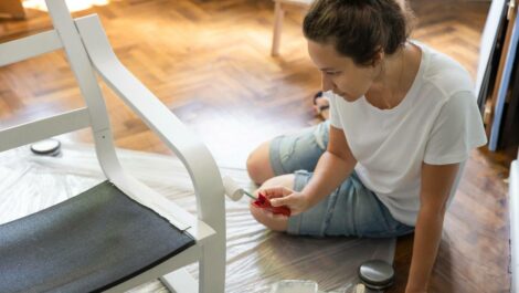 Woman painting a chair in her livingroom.