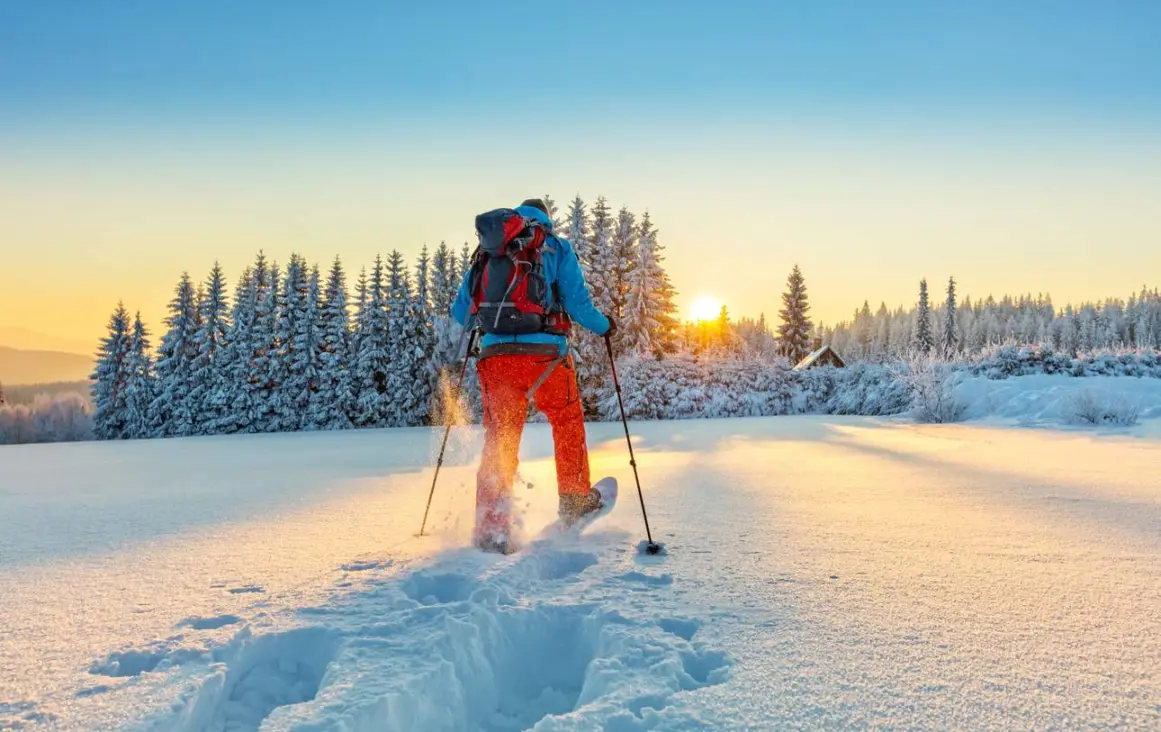 Snowshoe walker trekking through powdery snow in the mountains.