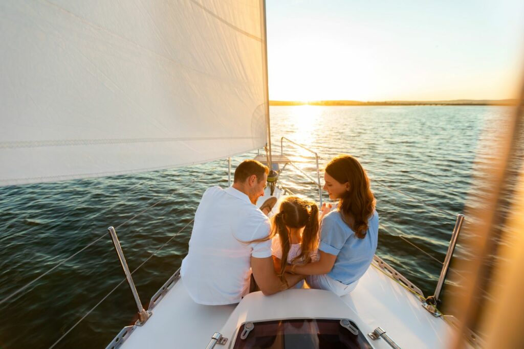 A family enjoys spending time together on a sailboat, while watching the beautiful sunset.