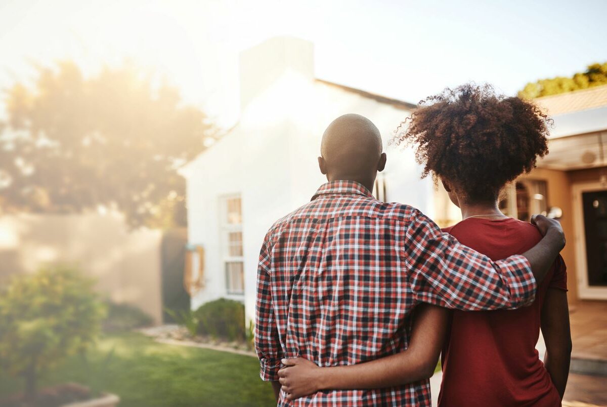 Back view of a young couple standing before a new home.