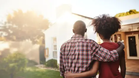 Back view of a young couple standing before a new home.