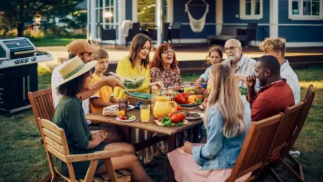 A joyful family having dinner at a backyard picnic table on a summer evening.