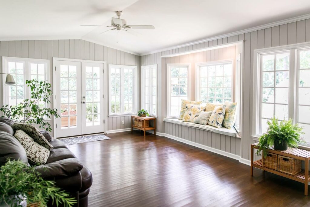 An open-concept room in a home with summery decor, plants, and large windows.