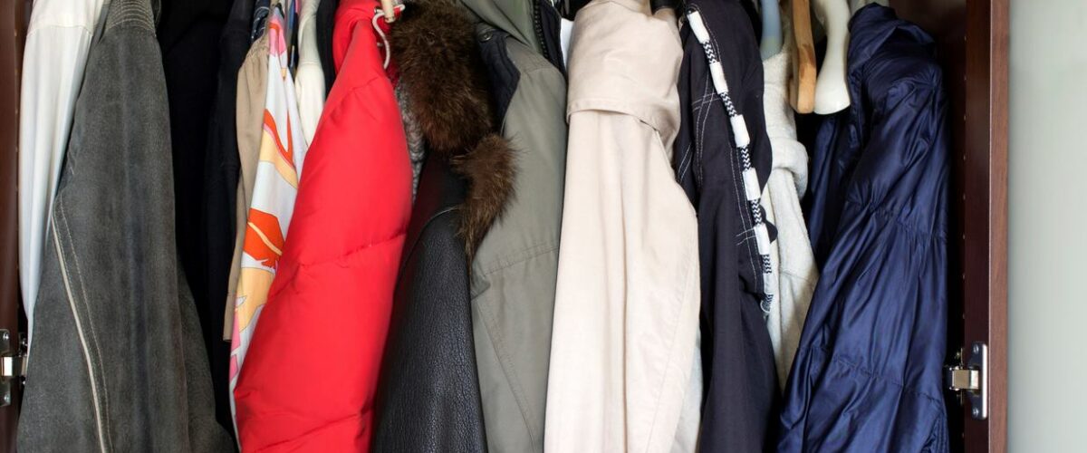 A closet full of winter coats and jackets on hangers.
