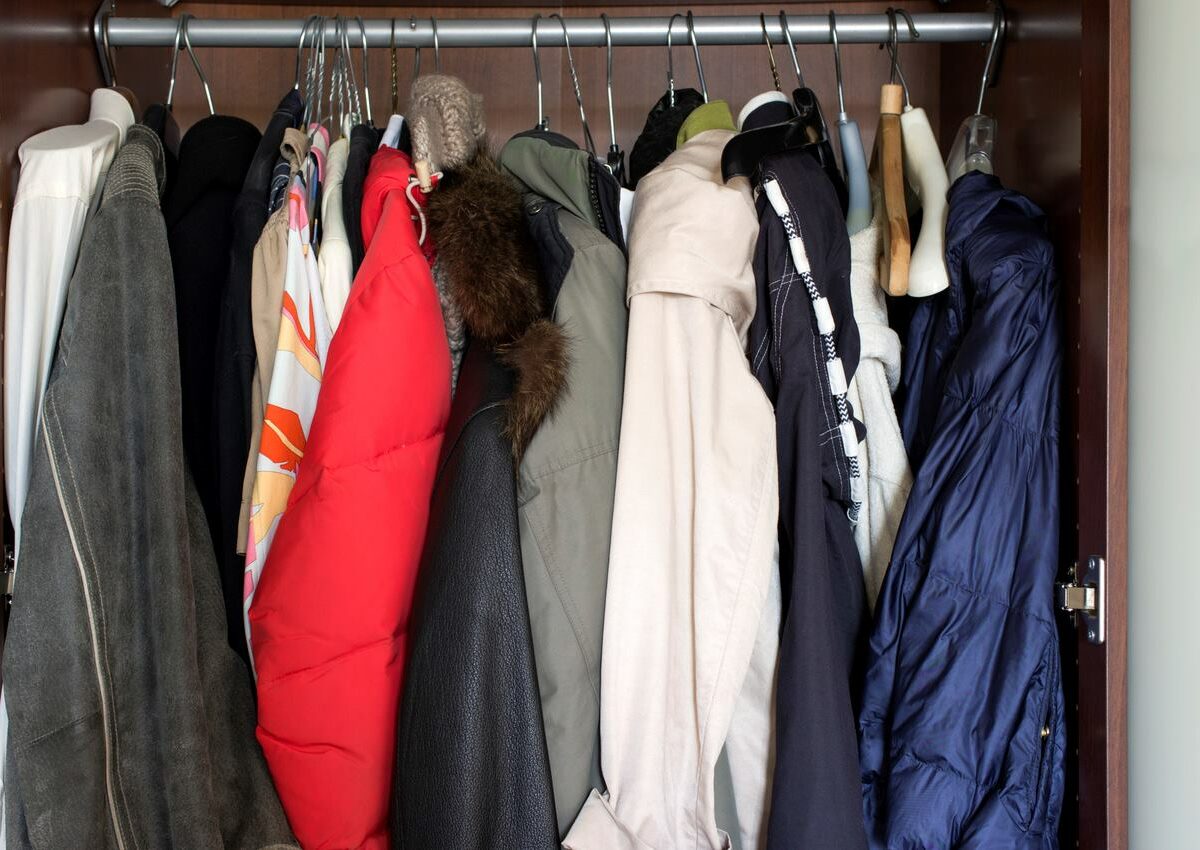 A closet full of winter coats and jackets on hangers.