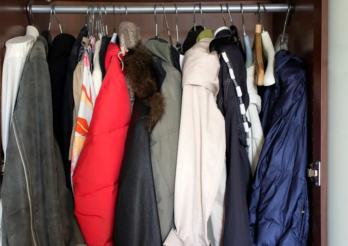 A closet full of winter coats and jackets on hangers.