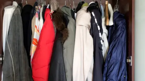 A closet full of winter coats and jackets on hangers.