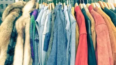 A clothing rack filled with vintage coats and jackets for sale at a flea market.