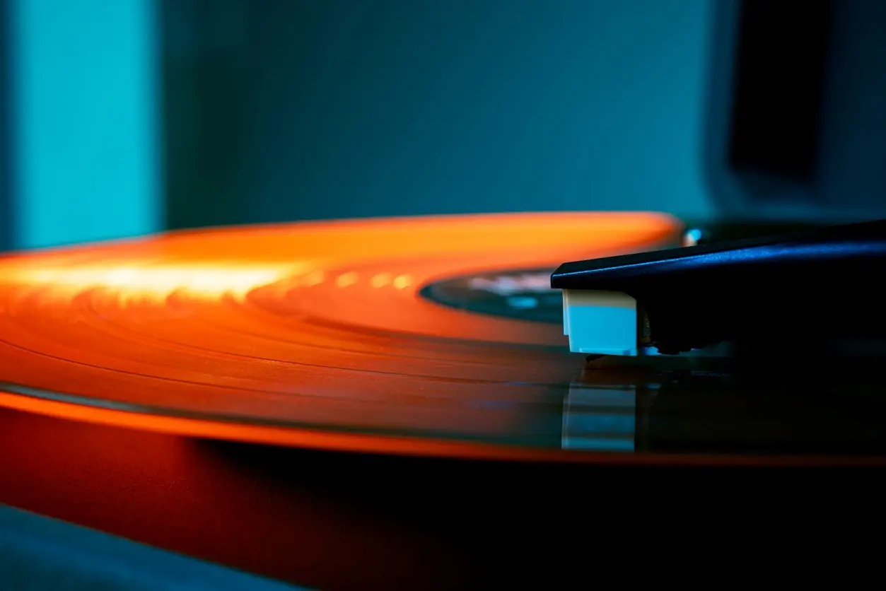 An orange vinyl record is played on a turntable. 