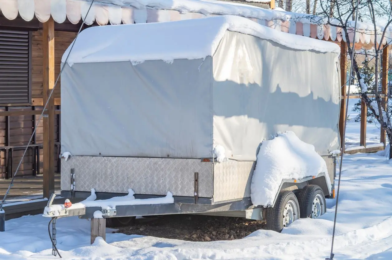 An RV with a cover over it protects it from the snow. 