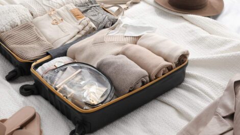An open suitcase on a bed with neatly arranged clothing, toiletries, and travel essentials.
