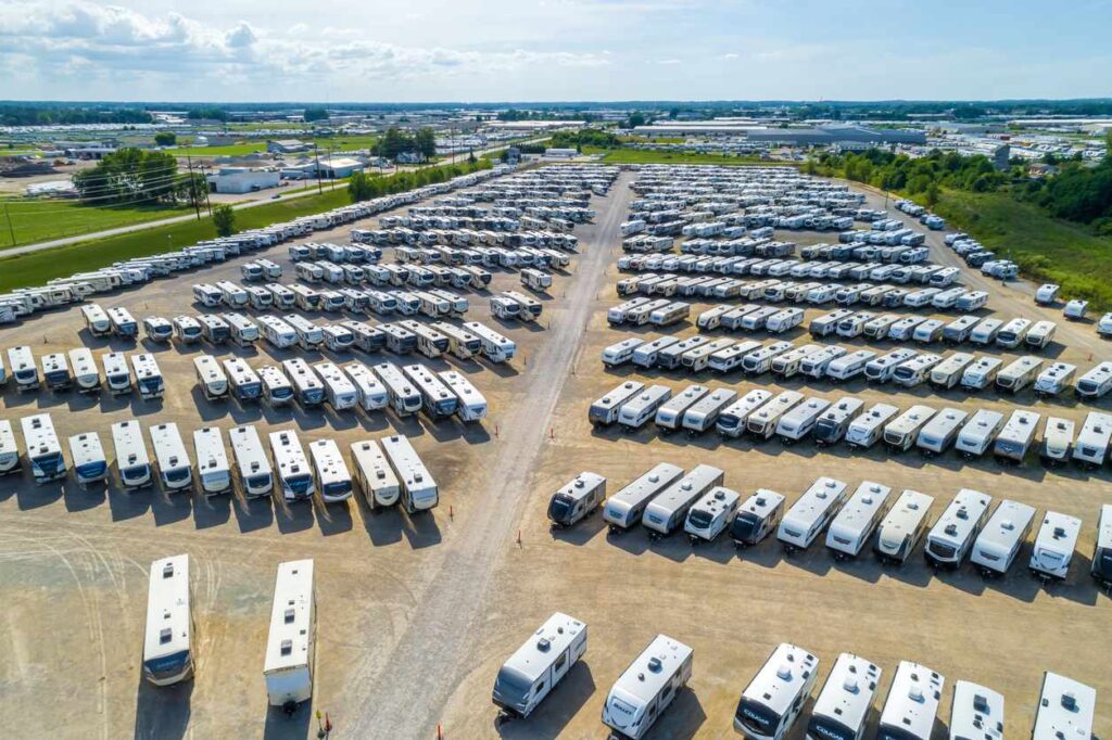 Aerial view of an organized outdoor RV storage facility with multiple motorhomes parked in rows.