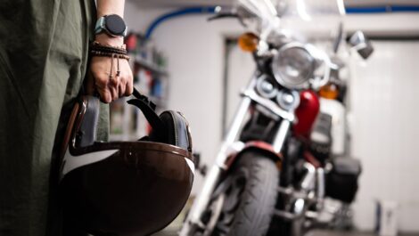 person holding a helmet next to a motorcycled stored in a garage
